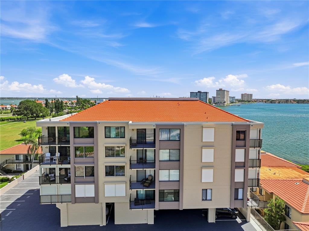 An aerial view of a multi-story apartment building with a red tile roof near water — 6104 PALMA DEL MAR BOULEVARD S UNIT 404, ST PETERSBURG, FL