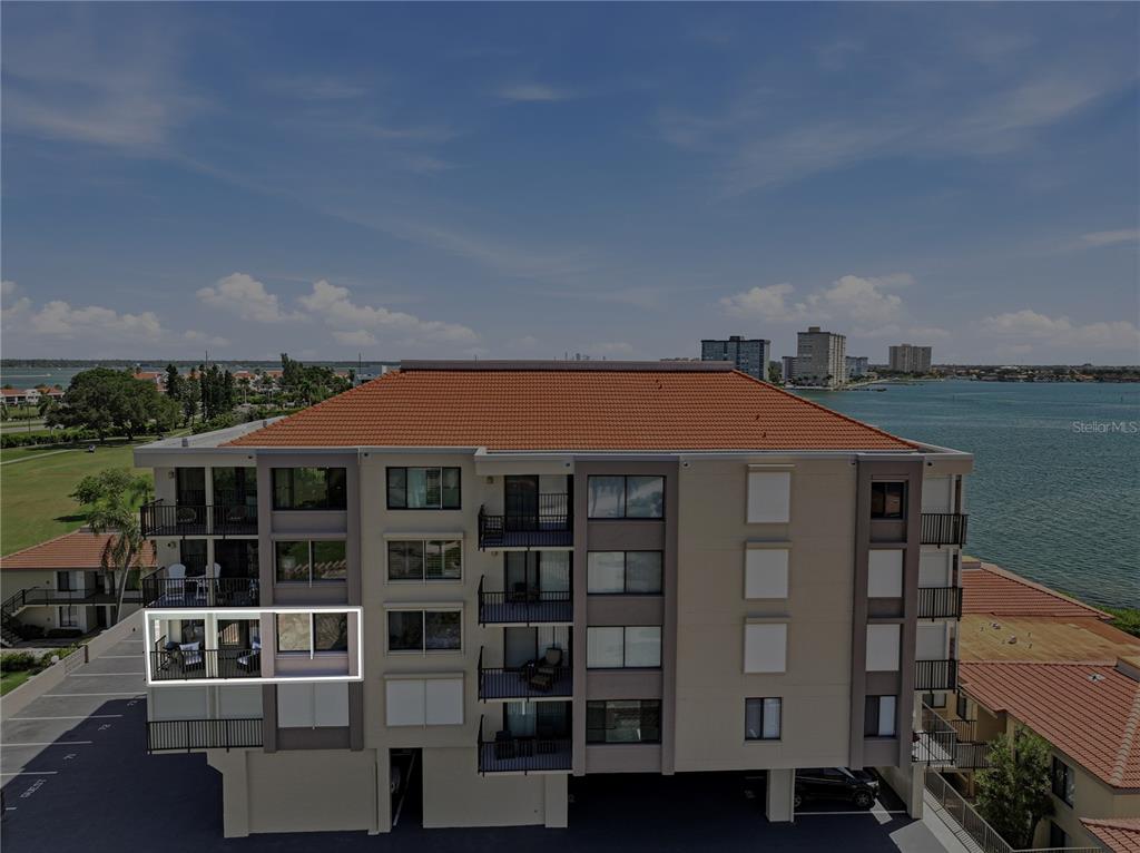An exterior view of a multi-story apartment building with balconies overlooking a body of water — 6104 PALMA DEL MAR BOULEVARD S UNIT 404, ST PETERSBURG, FL