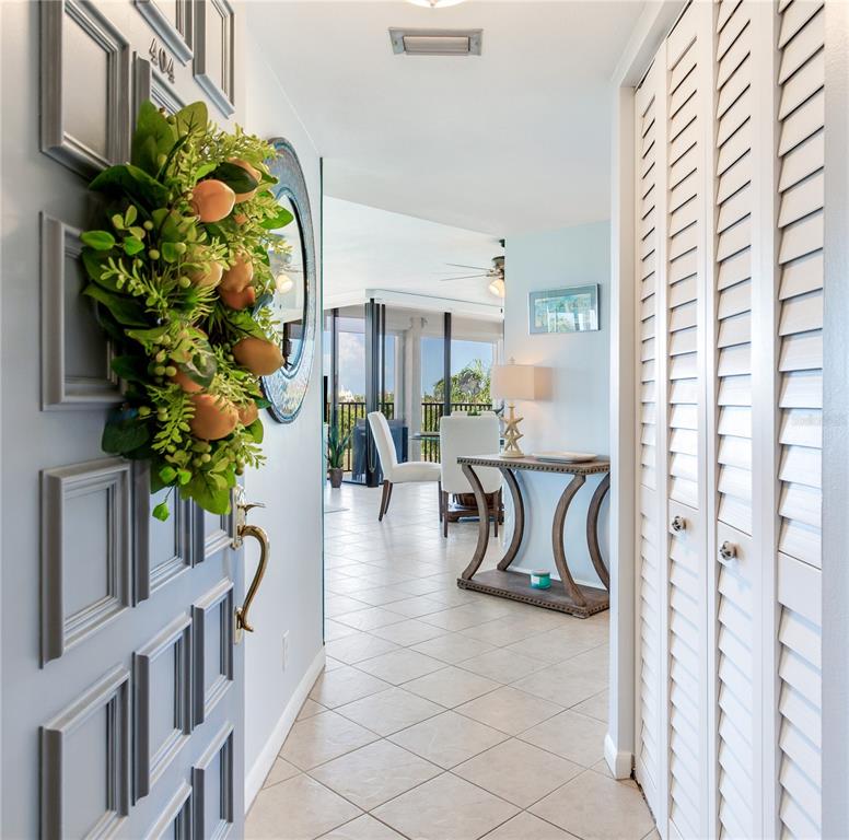 An entryway with a wreath-adorned door, tiled floors, and a view into a living area — 6104 PALMA DEL MAR BOULEVARD S UNIT 404, ST PETERSBURG, FL