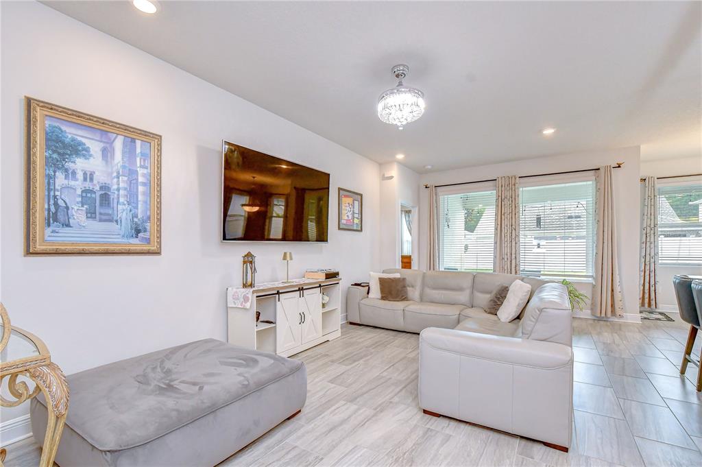 A living room features a large sectional sofa, a wall-mounted television, and tile flooring — 15371 CARAVAN AVENUE, ODESSA, FL