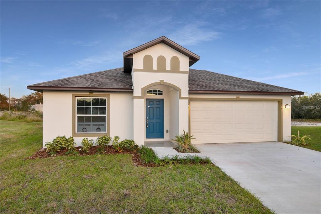 A single-story house with a blue front door, white stucco walls, and a two-car garage — 1409 HILLSBOROUGH WAY, KISSIMMEE, FL