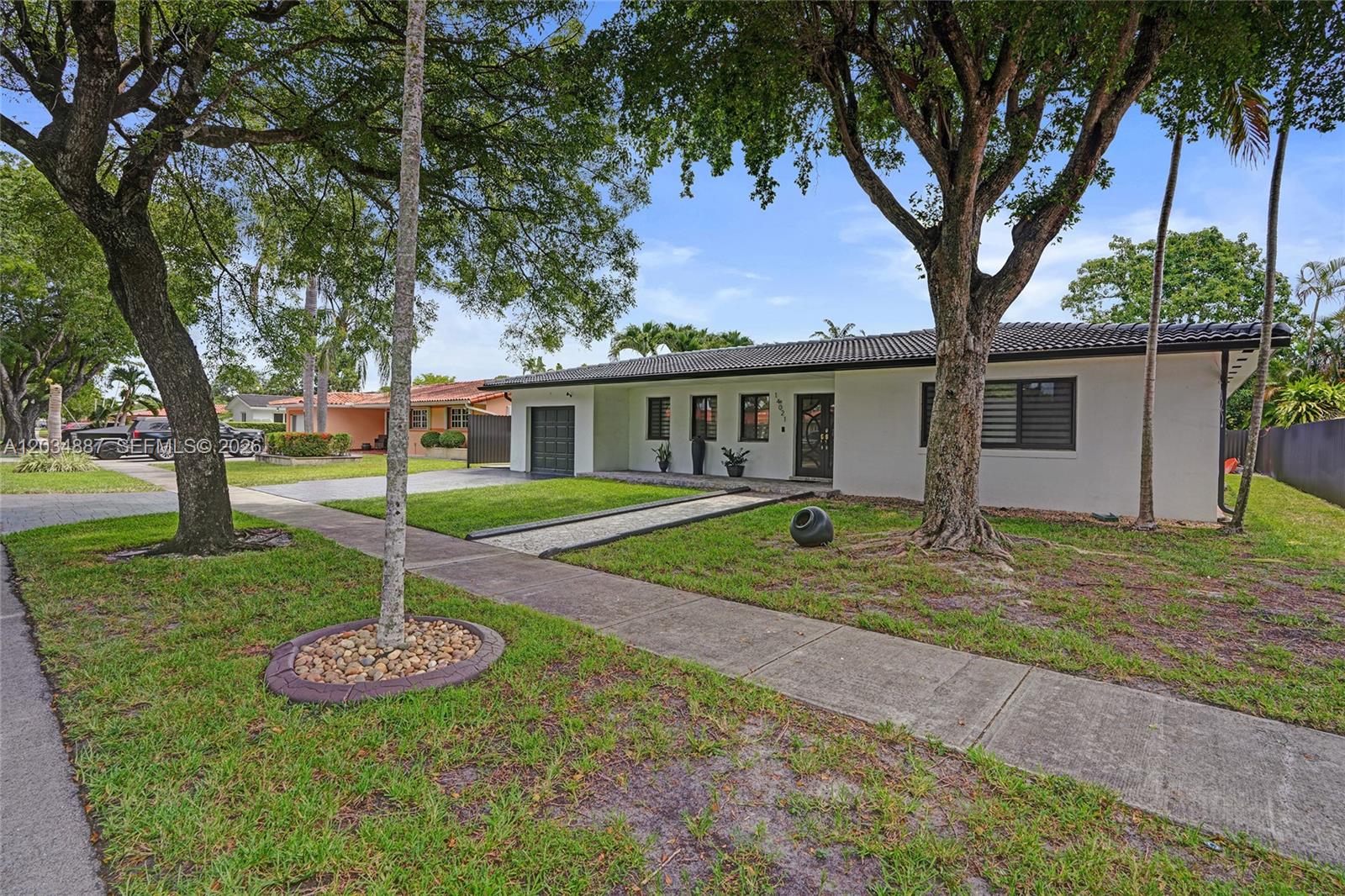 A single-story white house with a dark tiled roof, a garage, and mature trees — 14021 Cypress Ct, Miami Lakes FL 33014, MIAMI LAKES, FL