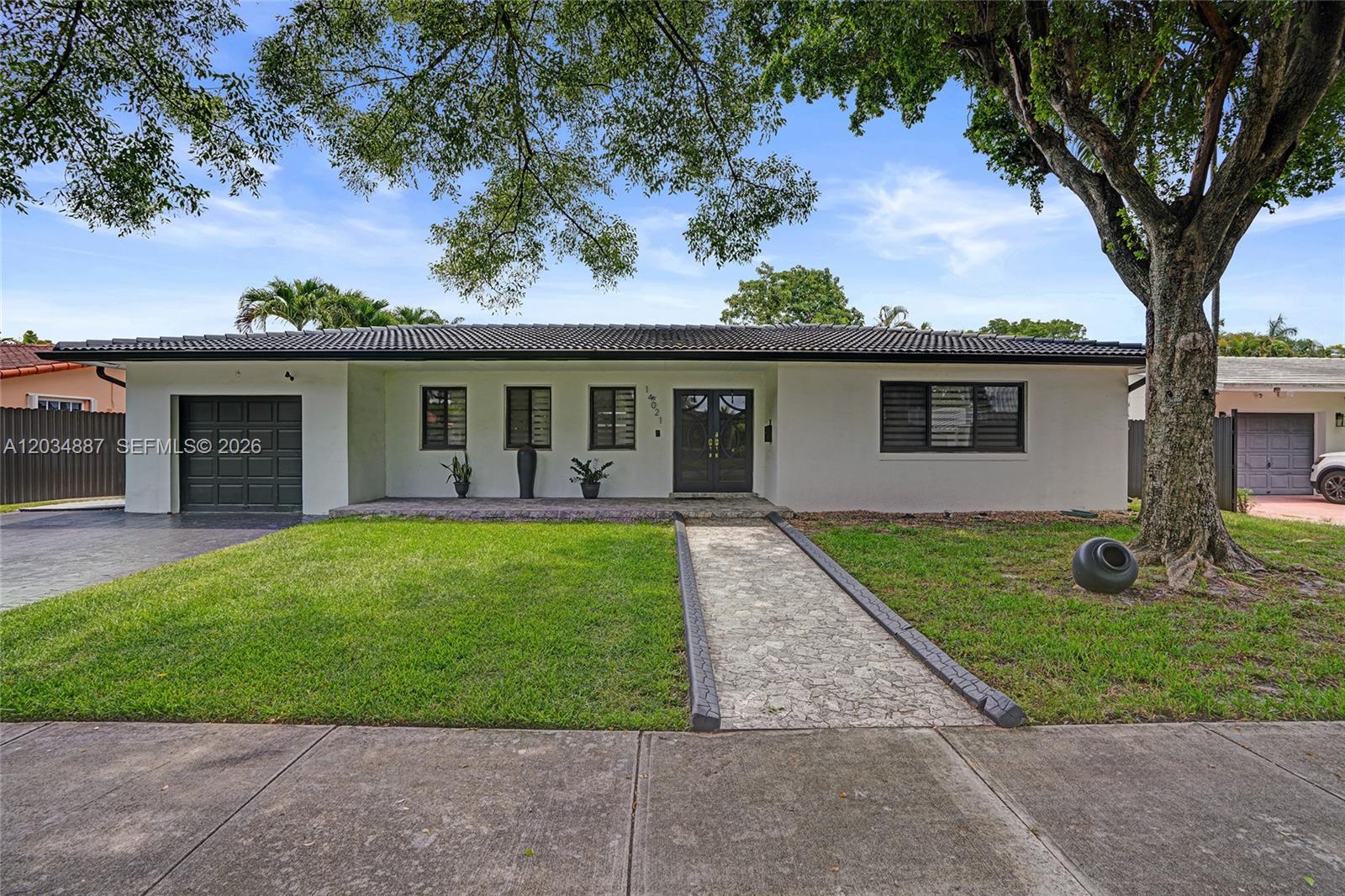 A single-story white house features a dark tiled roof, a garage, and a stone walkway — 14021 Cypress Ct, Miami Lakes FL 33014, MIAMI LAKES, FL