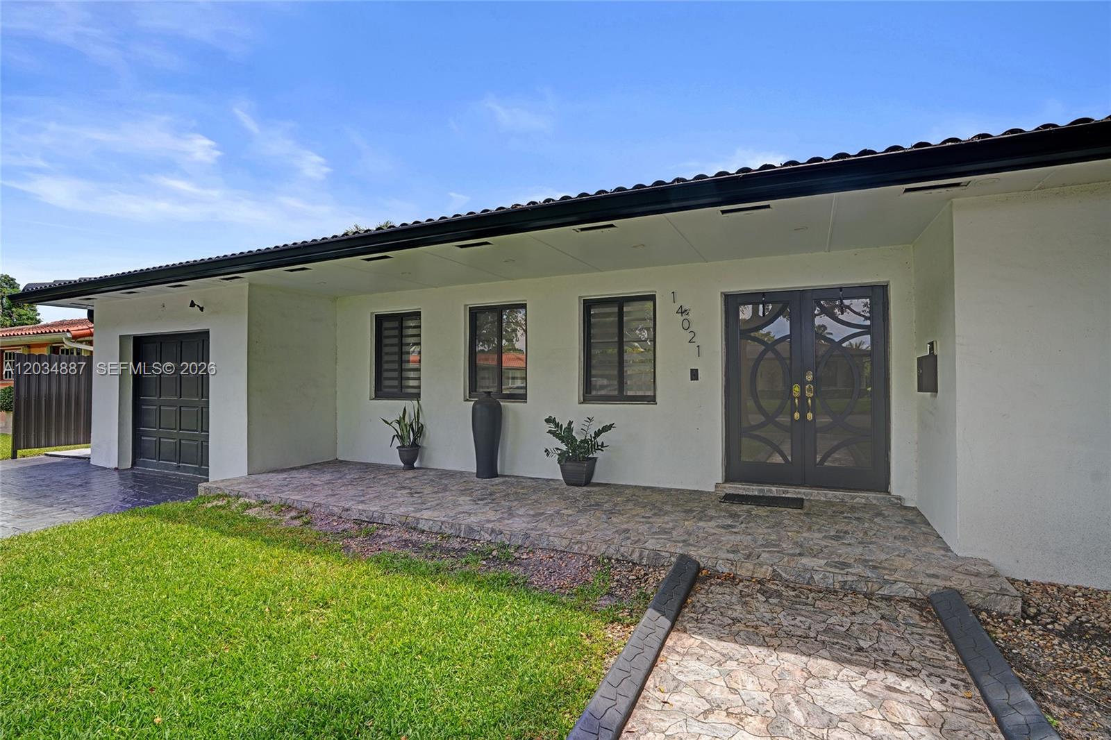 The exterior of a single-story house features a stone porch, double doors, and a garage — 14021 Cypress Ct, Miami Lakes FL 33014, MIAMI LAKES, FL