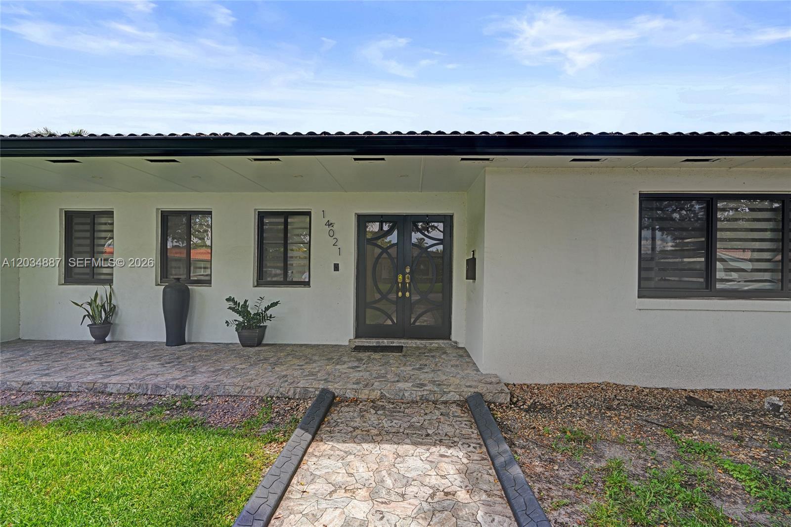 The exterior of a single-story house features a stone walkway leading to double glass doors — 14021 Cypress Ct, Miami Lakes FL 33014, MIAMI LAKES, FL