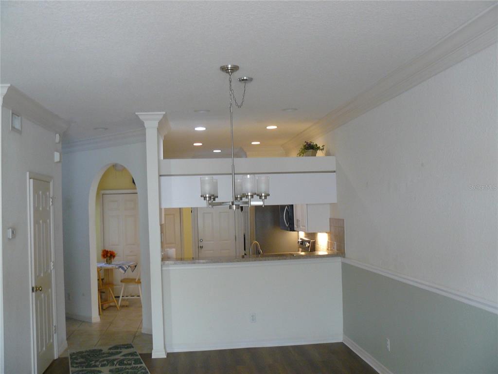 A view of a kitchen with a breakfast bar, pendant lighting, and an arched doorway — 8628 SWEET MAGNOLIA PLACE, SEMINOLE, FL