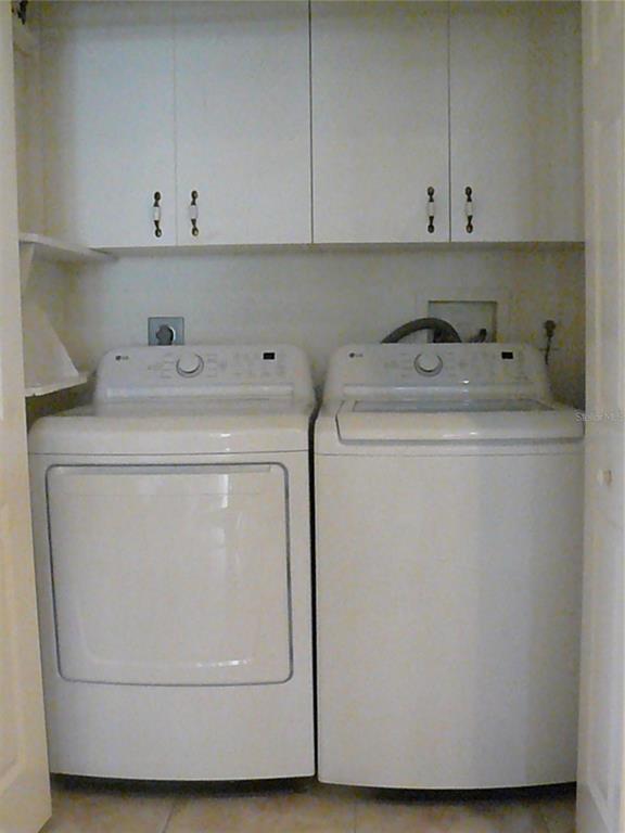 A laundry closet features a white washer and dryer beneath white upper cabinets — 8628 SWEET MAGNOLIA PLACE, SEMINOLE, FL