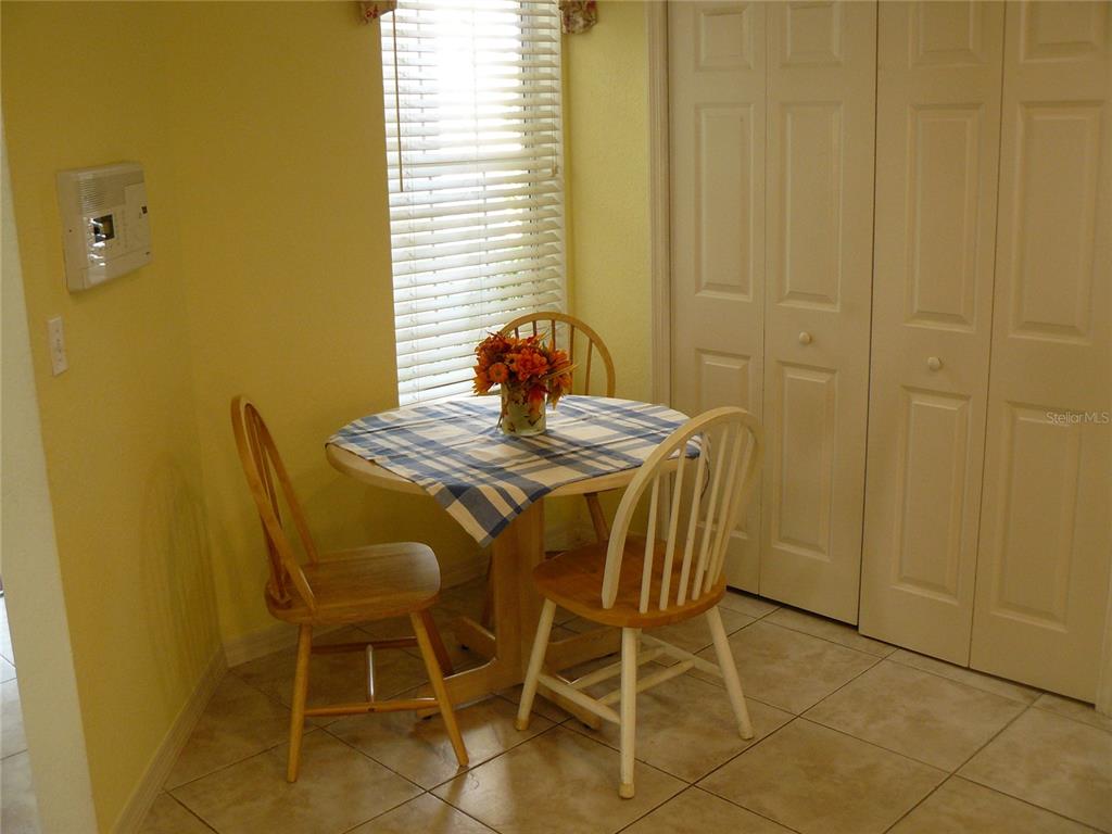 A small breakfast nook features a round table with two chairs, tile flooring, and blinds — 8628 SWEET MAGNOLIA PLACE, SEMINOLE, FL
