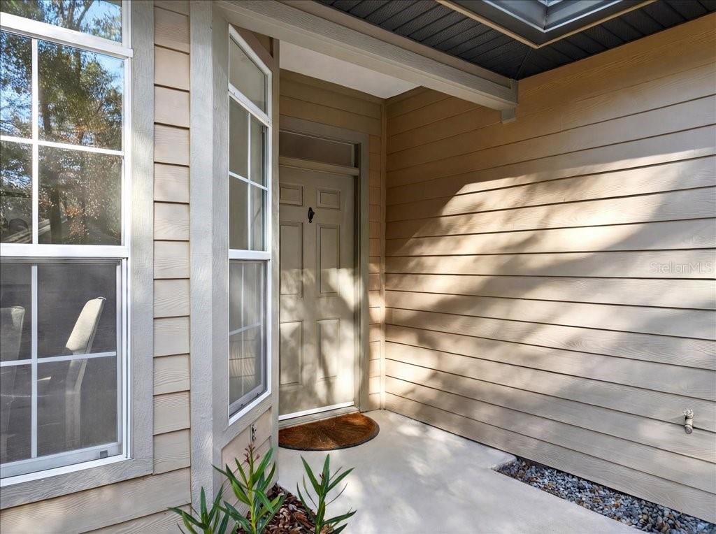 A beige front door is recessed under a covered entryway with horizontal siding — 4412 SW 101ST DRIVE, GAINESVILLE, FL