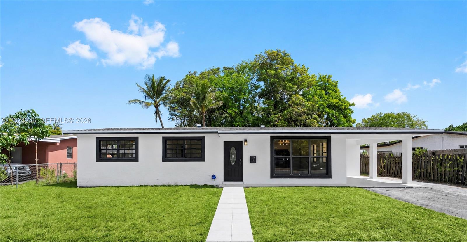 A white single-story house with black window frames and a front carport under a blue sky — 4830 NW 13th St, Lauderhill FL 33313, LAUDERHILL, FL