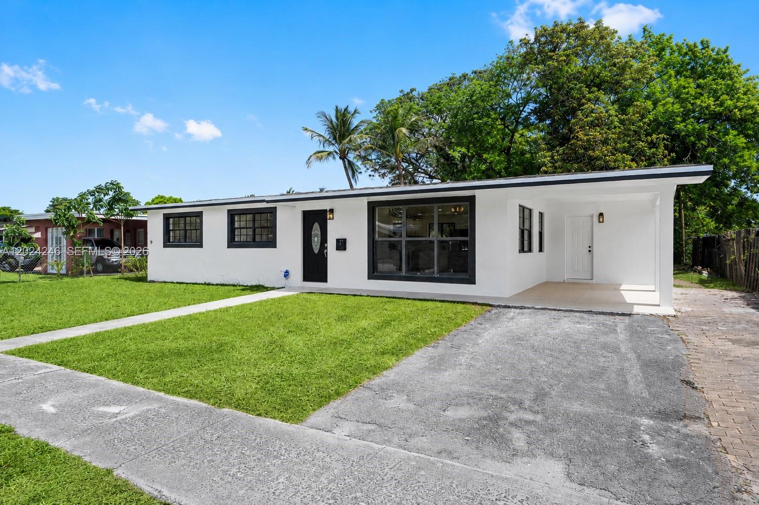 A white single-story house with a black-trimmed front door, large window, and attached carport — 4830 NW 13th St, Lauderhill FL 33313, LAUDERHILL, FL