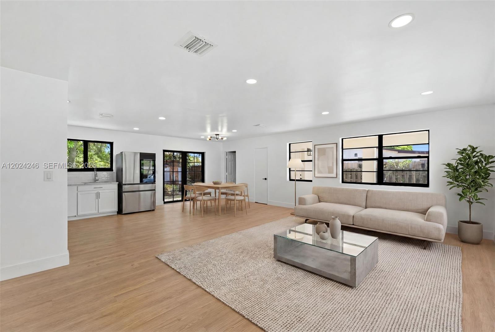 An open-concept living and dining area features light wood flooring, white walls, and modern furniture — 4830 NW 13th St, Lauderhill FL 33313, LAUDERHILL, FL
