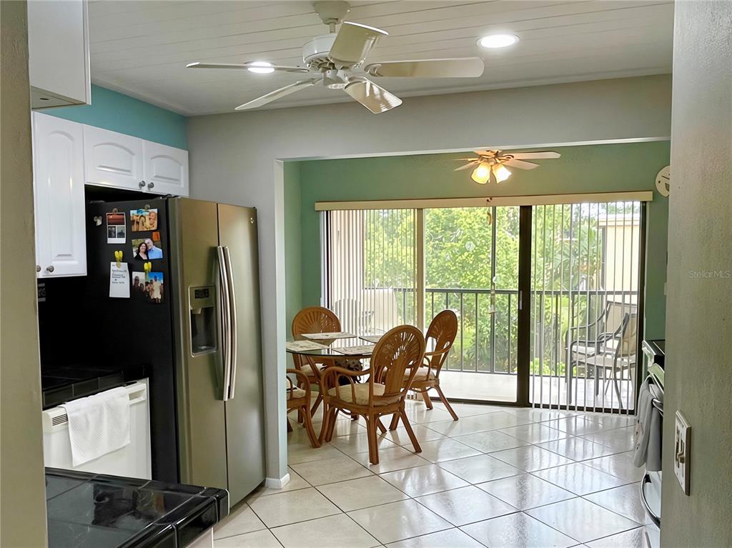 A kitchen with white cabinets and a stainless steel refrigerator opens to a dining area — 305 30TH AVENUE W UNIT A307, BRADENTON, FL
