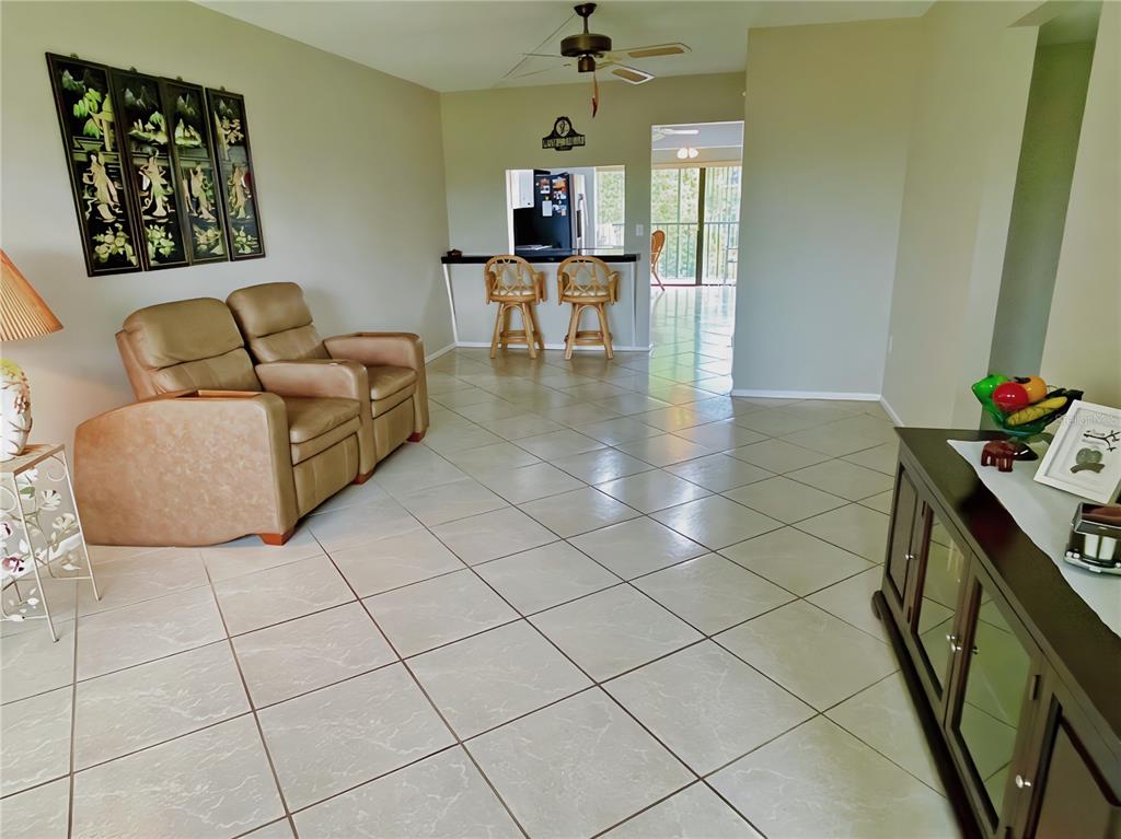 A living room with tan leather recliners, tile flooring, and a breakfast bar with stools — 305 30TH AVENUE W UNIT A307, BRADENTON, FL