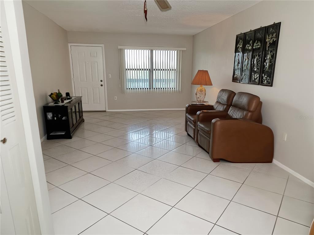 A living room features light tile flooring, a brown leather loveseat, and a front door — 305 30TH AVENUE W UNIT A307, BRADENTON, FL