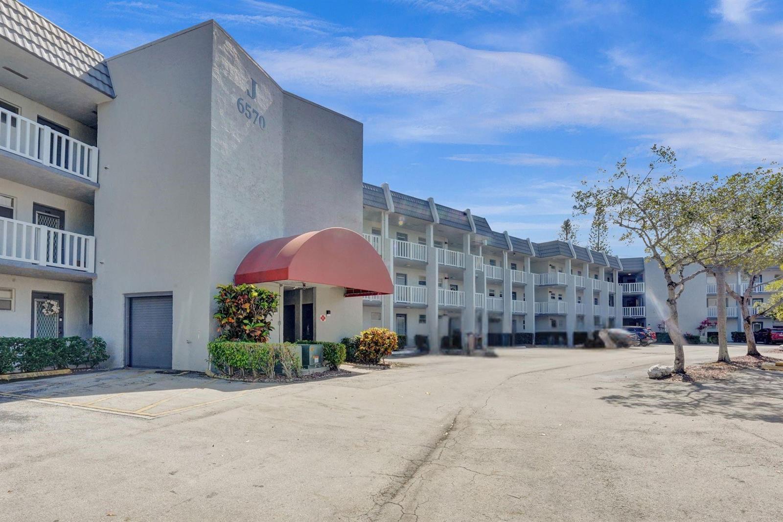 A multi-story apartment building with a red awning over the entrance and white balconies — 6570 Royal Palm Boulevard # 210j, Margate FL 33063, MARGATE, FL