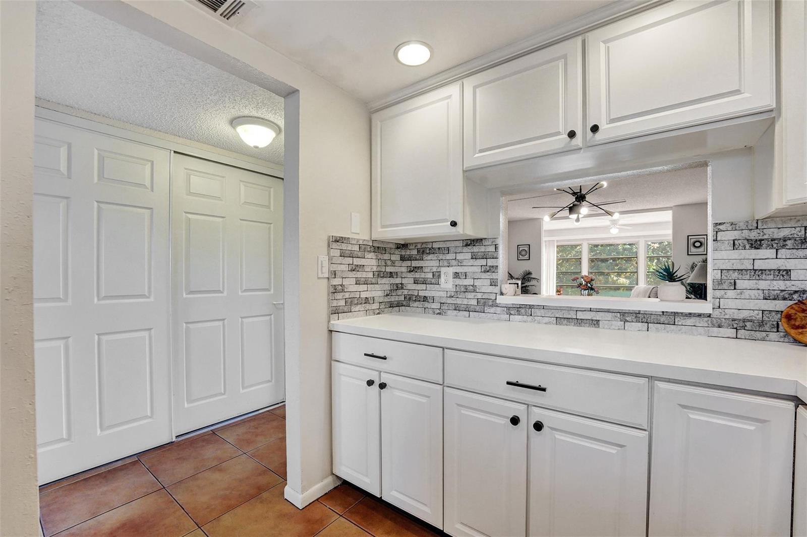 A kitchen area features white cabinets, a white countertop, and a gray brick-patterned backsplash — 6570 Royal Palm Boulevard # 210j, Margate FL 33063, MARGATE, FL
