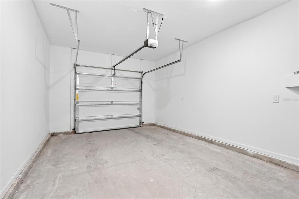 An empty garage features white walls, a concrete floor, and a sectional overhead door — 4839 SW 81ST LOOP, OCALA, FL