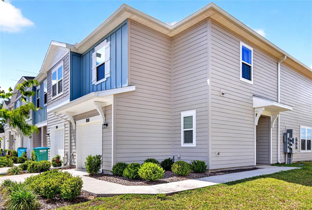 A two-story townhouse exterior features beige horizontal siding, blue vertical accents, and a garage — 4839 SW 81ST LOOP, OCALA, FL