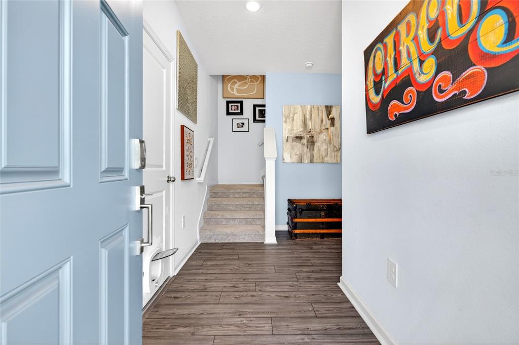 An entryway features wood-look flooring, a staircase with carpet, and a blue front door — 4839 SW 81ST LOOP, OCALA, FL