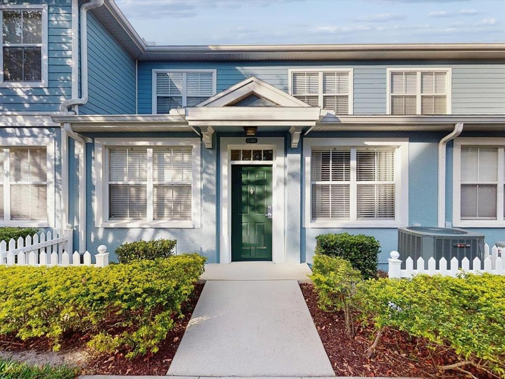 A blue two-story townhouse features a green front door, white trim, and a small walkway — 4004 SAN GALLO DRIVE UNIT 104, KISSIMMEE, FL
