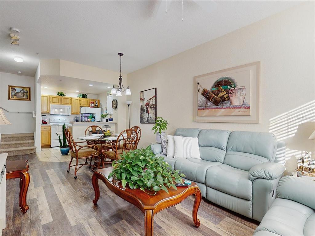 A living room and dining area with light blue leather seating and wood-look flooring — 4004 SAN GALLO DRIVE UNIT 104, KISSIMMEE, FL