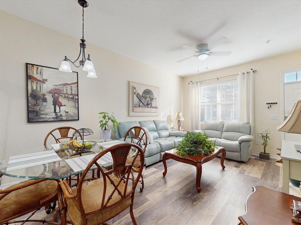A living and dining room area with light-colored walls, wood-look flooring, and a ceiling fan — 4004 SAN GALLO DRIVE UNIT 104, KISSIMMEE, FL
