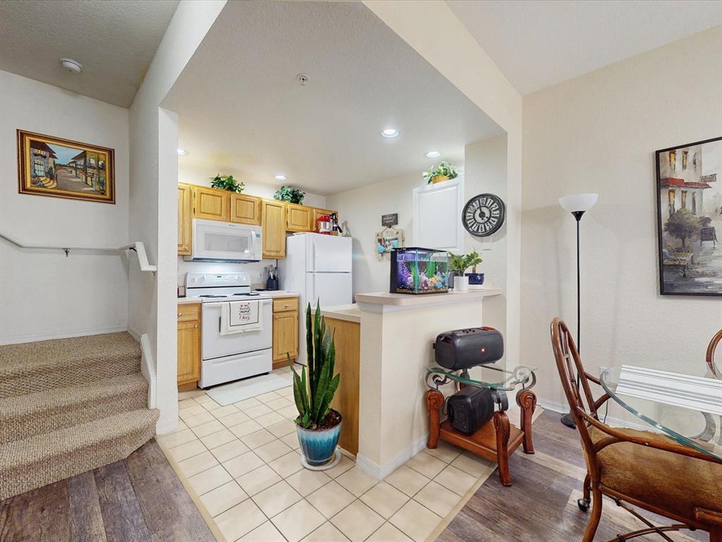 A kitchen with light wood cabinets and white appliances opens to a dining area — 4004 SAN GALLO DRIVE UNIT 104, KISSIMMEE, FL
