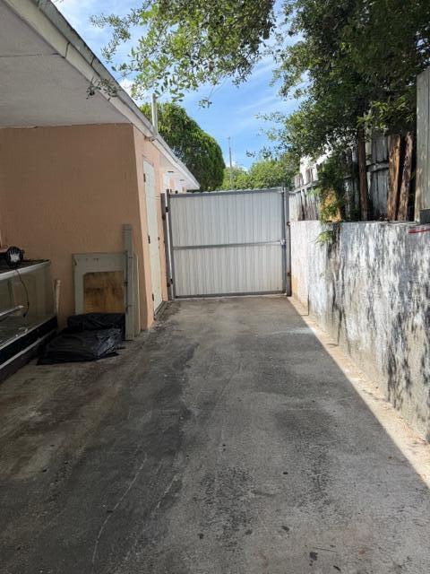 A concrete driveway leads to a white metal gate between a building and a wall — 2975 NW 96th Street, Miami FL 33147, MIAMI, FL
