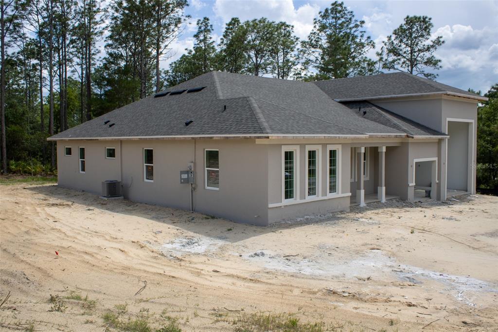 A beige house with a large attached garage sits on a grassy lot with trees — 6412 W EL DORADO LANE, BEVERLY HILLS, FL