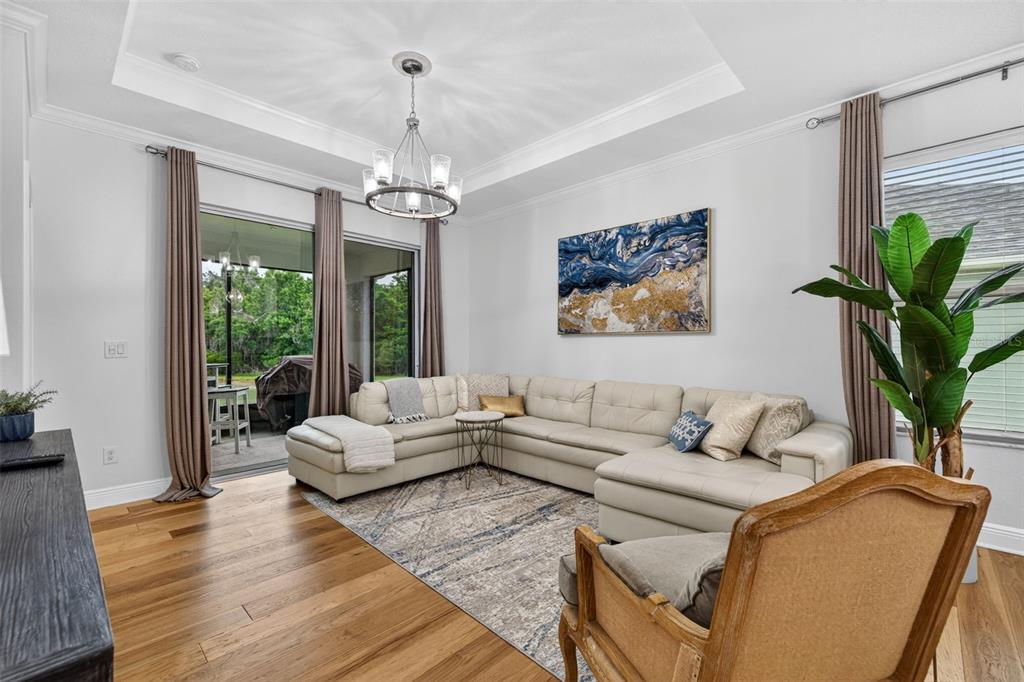 A living room features a large sectional sofa, a patterned rug, and sliding glass doors — 19333 FORT KING RUN, BROOKSVILLE, FL