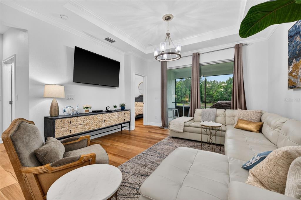 A living room features a white sectional sofa, a wooden media console, and hardwood floors — 19333 FORT KING RUN, BROOKSVILLE, FL
