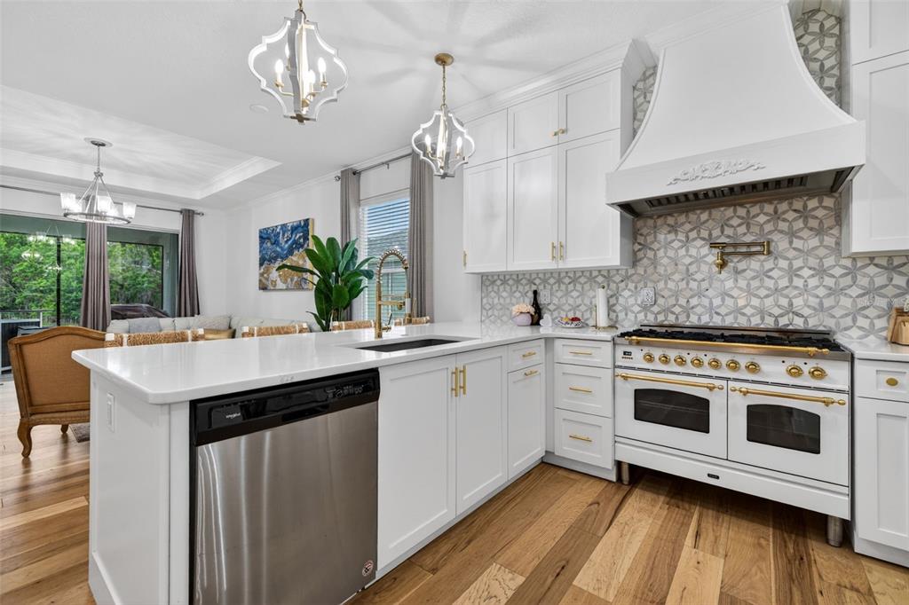 A bright kitchen features white cabinets, a large island, stainless appliances, and a patterned backsplash — 19333 FORT KING RUN, BROOKSVILLE, FL