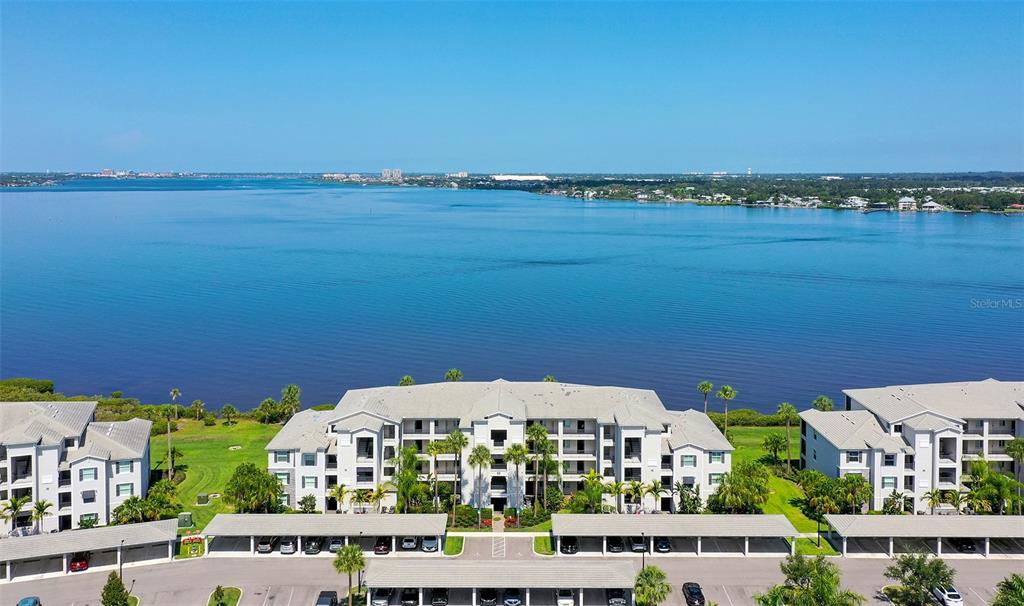An aerial view shows a multi-story apartment complex situated along a large body of water — 910 TIDEWATER SHORES LOOP UNIT 103, BRADENTON, FL