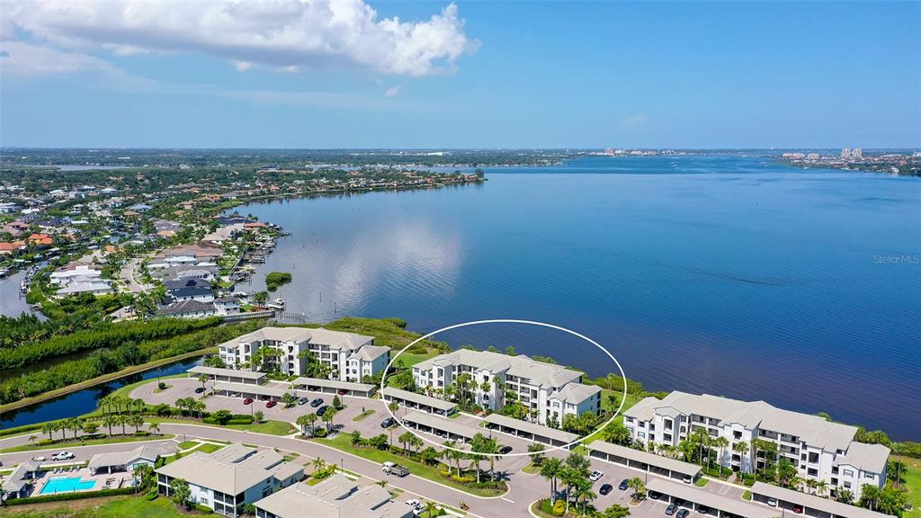 An aerial view shows a multi-story apartment complex situated along a large body of water — 910 TIDEWATER SHORES LOOP UNIT 103, BRADENTON, FL