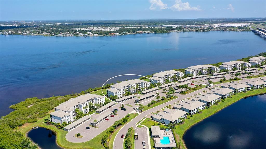 An aerial view shows a multi-story apartment building circled within a waterfront residential complex — 910 TIDEWATER SHORES LOOP UNIT 103, BRADENTON, FL