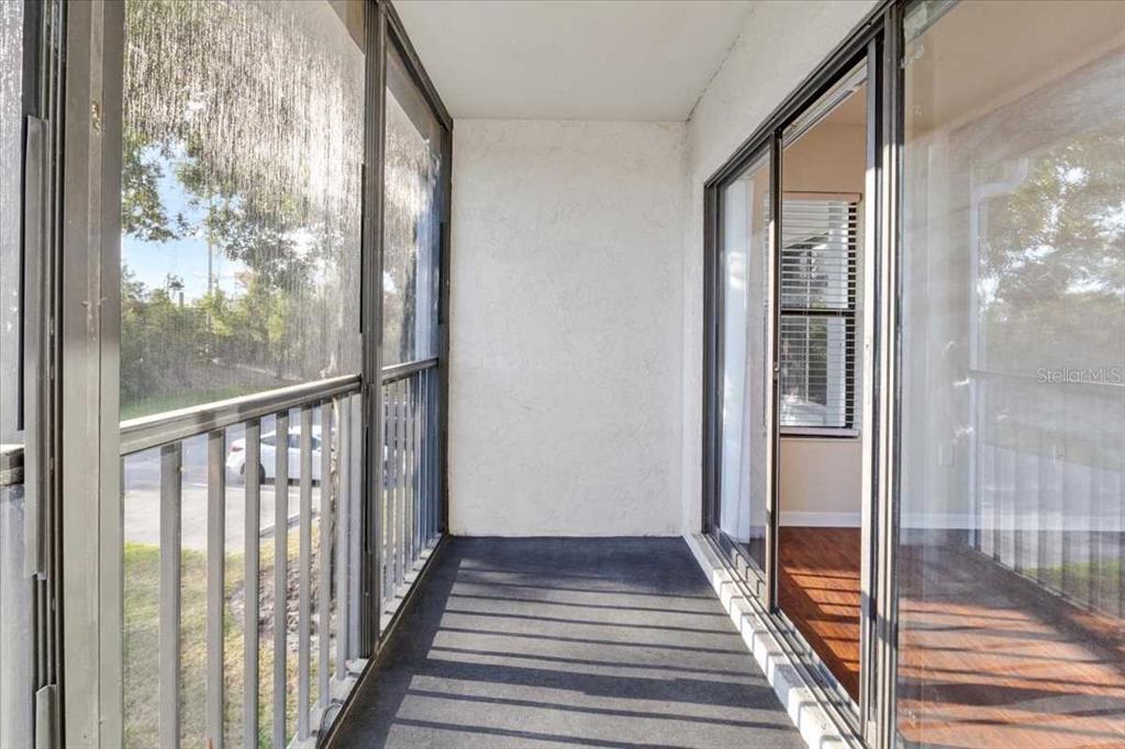 A screened-in balcony with a dark floor, white walls, and sliding glass doors — 1127 PINE RIDGE CIRCLE W UNIT A2, TARPON SPRINGS, FL