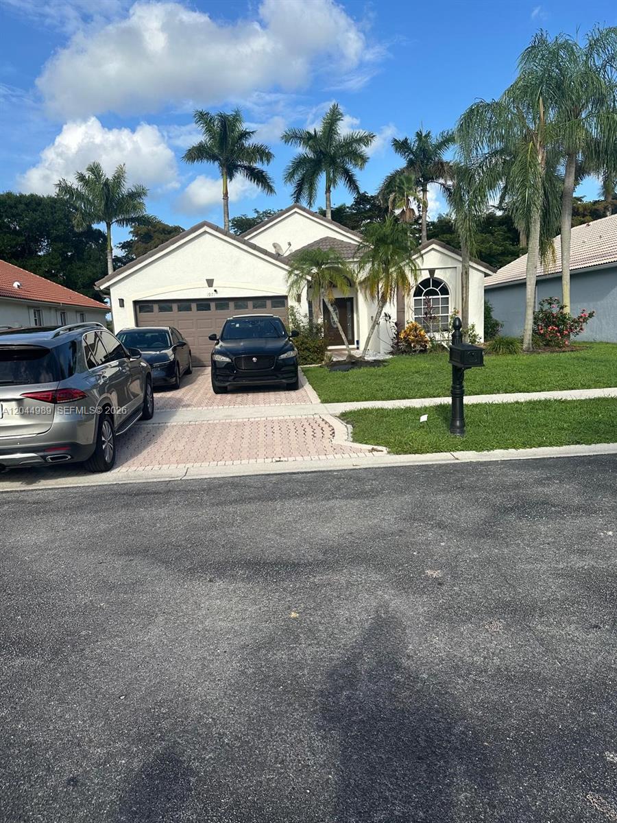 A single-story house with a two-car garage and palm trees in the front yard — 1971 Oak Berry Cir, Wellington FL 33414, WELLINGTON, FL