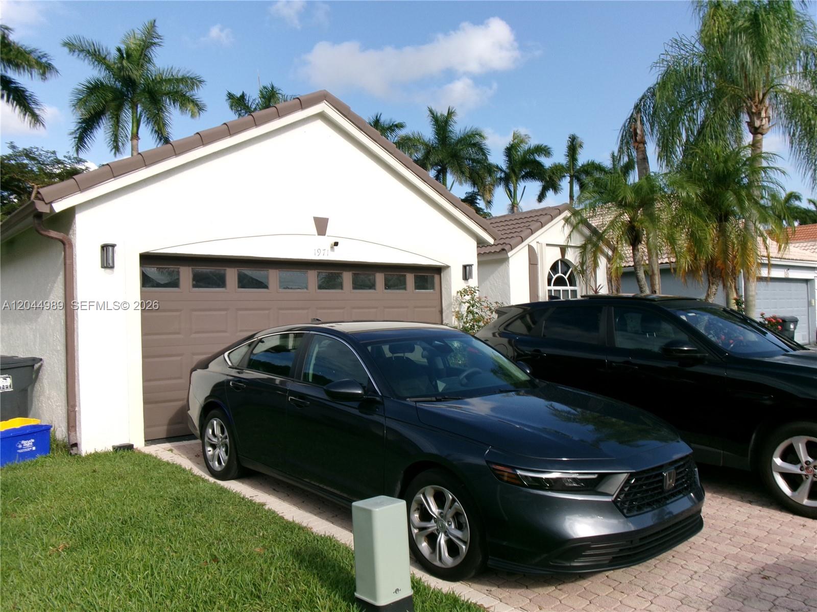 A dark sedan is parked in the driveway of a house with a garage — 1971 Oak Berry Cir, Wellington FL 33414, WELLINGTON, FL