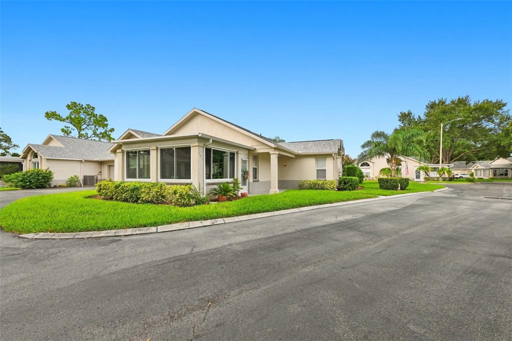 A single-story house with a sunroom and a paved driveway under a clear blue sky — 1124 GOLFVIEW WOODS DRIVE UNIT na, SUN CITY CENTER, FL