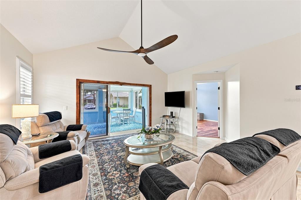 A living room features a vaulted ceiling, a ceiling fan, and a sliding glass door — 1124 GOLFVIEW WOODS DRIVE UNIT na, SUN CITY CENTER, FL