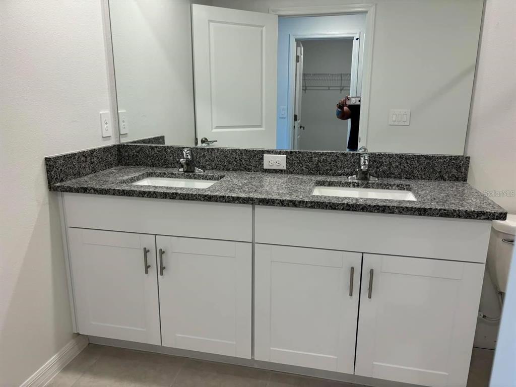 A bathroom vanity with a granite countertop, dual sinks, and white cabinets — 8254 CORNER PINE WAY, NEW PORT RICHEY, FL