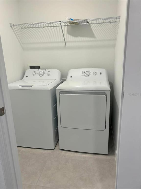 A laundry closet contains a white top-loading washing machine and a matching dryer — 8254 CORNER PINE WAY, NEW PORT RICHEY, FL