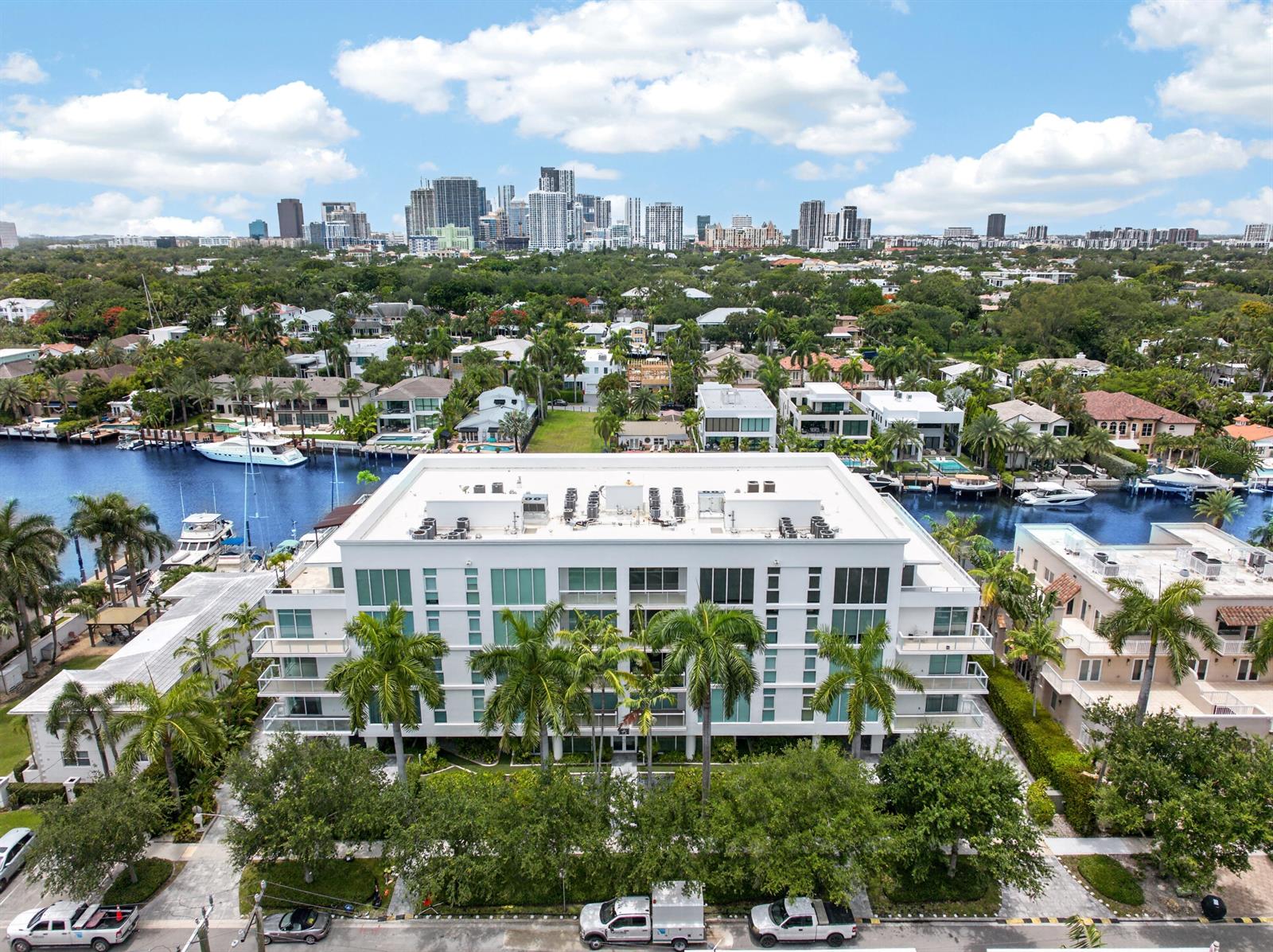 An aerial view of a white multi-story apartment building surrounded by palm trees and canals — 45 Hendricks Isle # 403, Fort Lauderdale FL 33301, FORT LAUDERDALE, FL