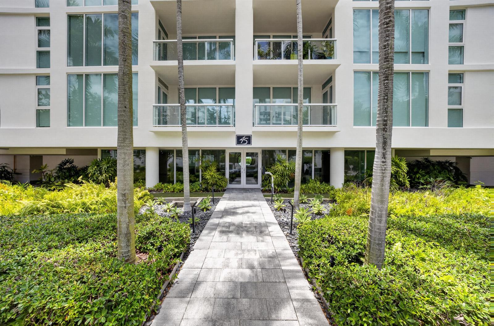 A paved walkway leads to the entrance of a white multi-story building with palm trees — 45 Hendricks Isle # 403, Fort Lauderdale FL 33301, FORT LAUDERDALE, FL