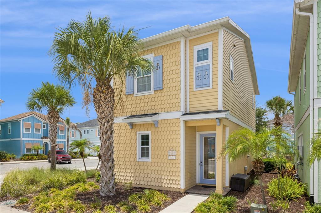 A two-story yellow house with shingle siding, blue shutters, and palm trees in the front — 8065 LOST SHAKER LANE, KISSIMMEE, FL