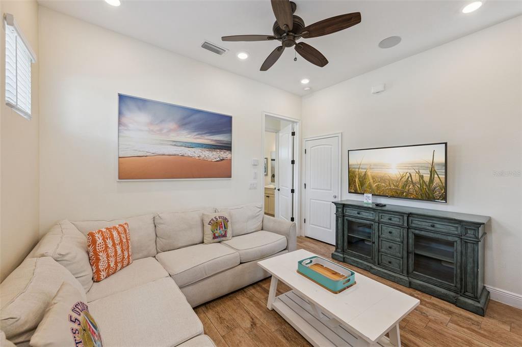 A living room features a sectional sofa, a white coffee table, and a wall-mounted television — 8065 LOST SHAKER LANE, KISSIMMEE, FL