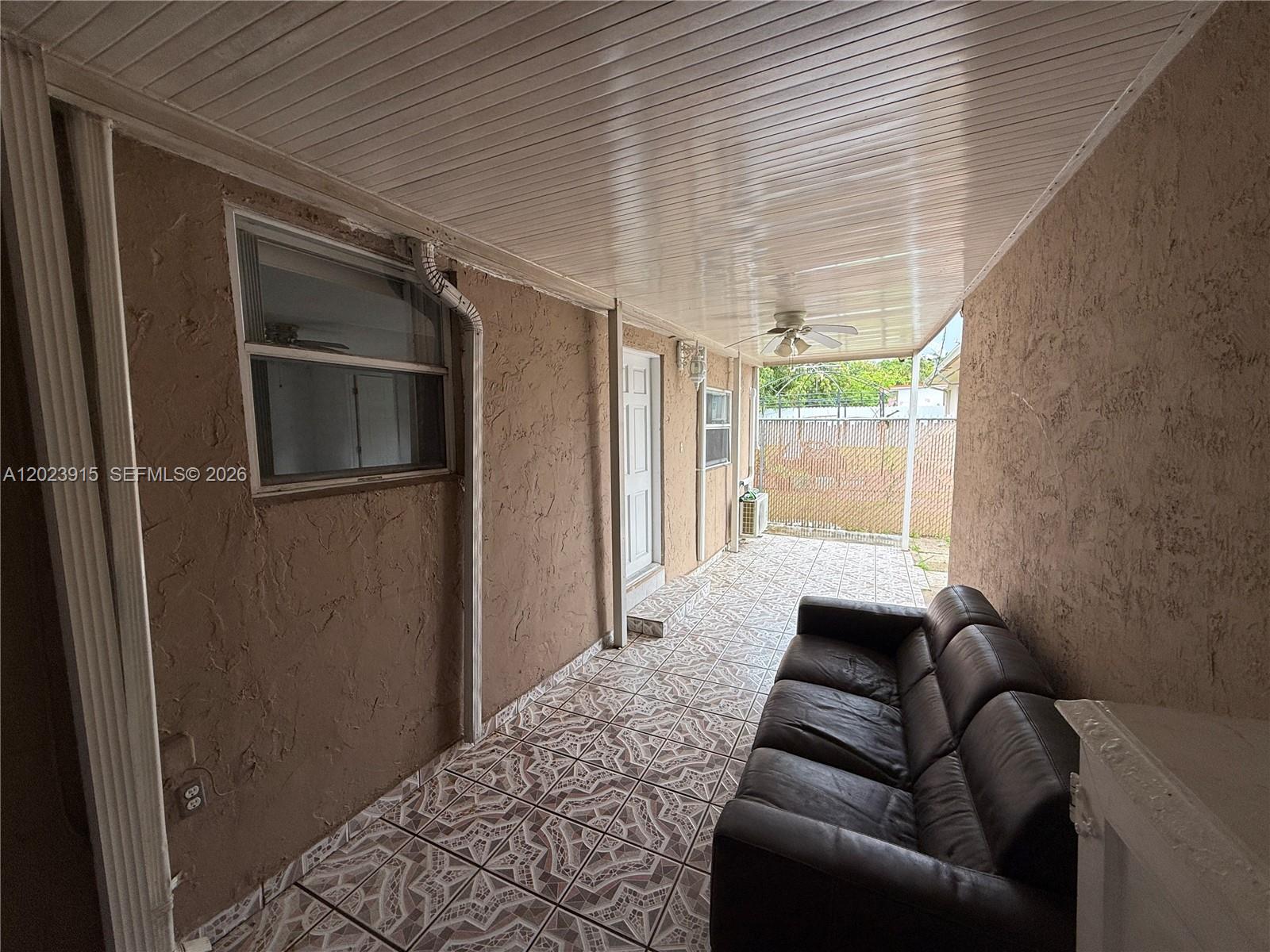 A covered patio features a dark leather sofa, patterned tile flooring, and textured tan walls — 3513 SW 4th St # 2, Miami FL 33135, MIAMI, FL
