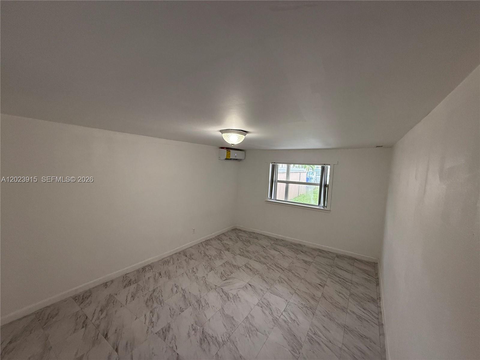 A small, empty room features white walls, marble-patterned tile flooring, and a wall-mounted air conditioner — 3513 SW 4th St # 2, Miami FL 33135, MIAMI, FL