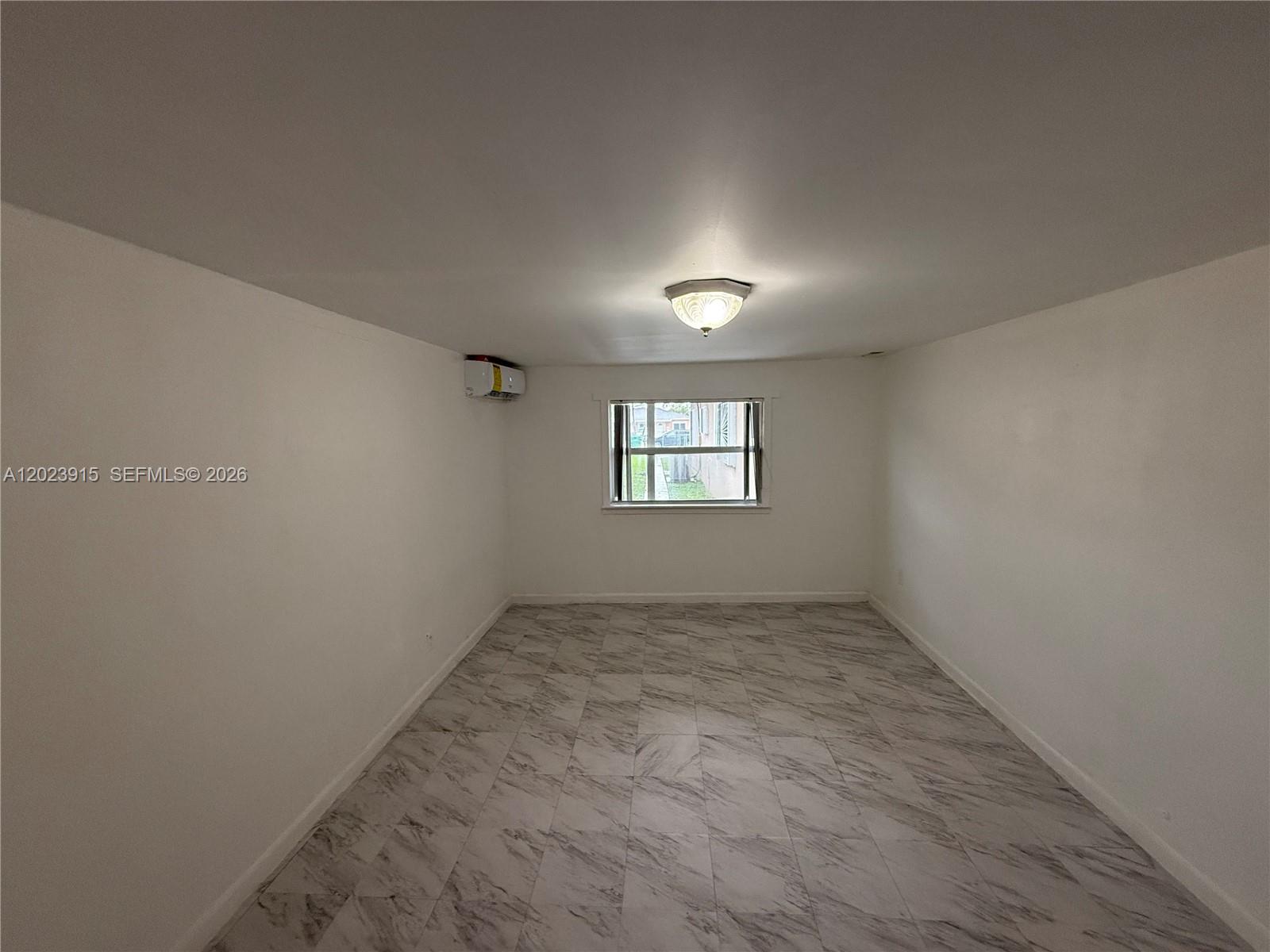 An empty room features white walls, marble-patterned tile flooring, a ceiling light, and a window — 3513 SW 4th St # 2, Miami FL 33135, MIAMI, FL